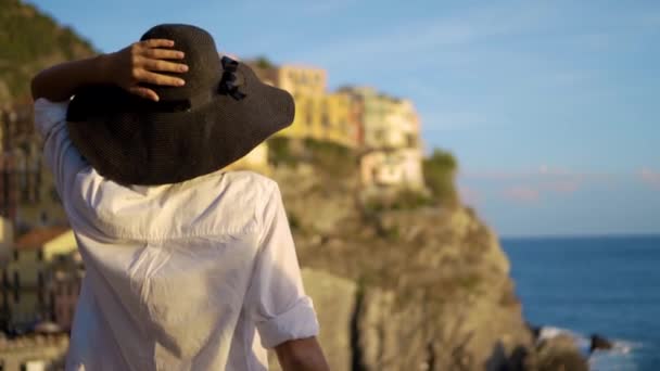 Chica en un sombrero mira a la ciudad de Manarola Italia — Vídeos de Stock