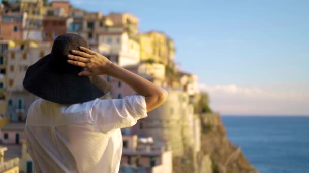 Chica en un sombrero mira a la ciudad de Manarola Italia — Vídeos de Stock