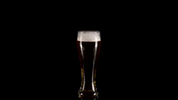 Rotacja szklankę piwa z pianki na czarnym tle — Wideo stockowe
