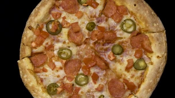 Ротация вкусной аппетитной пиццы на черном фоне — стоковое видео
