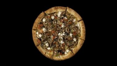 Tütsülenmiş sosis ve zeytin siyah bir zemin üzerine dönen pizza. Üstten görünüm merkezi yönlendirme