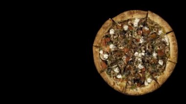 Tütsülenmiş sosis ve zeytin siyah bir zemin üzerine dönen pizza. Üstten görünüm merkezi yönlendirme