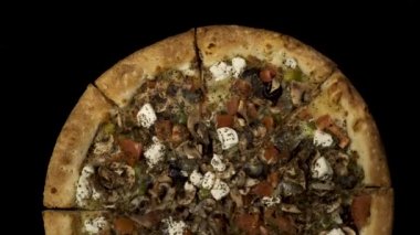 Tütsülenmiş sosis ve zeytin siyah bir zemin üzerine dönen pizza. Üstten görünüm merkezi yönlendirme