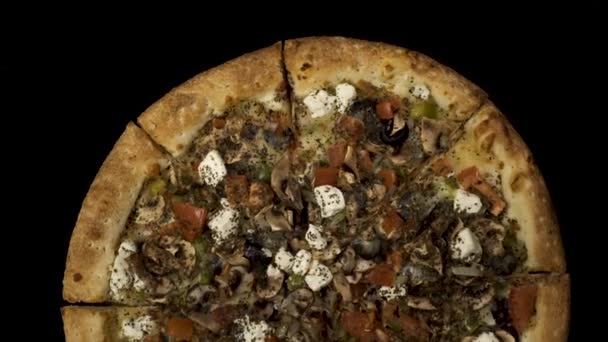 Eine rotierende Pizza mit Räucherwurst und Oliven auf schwarzem Hintergrund. Orientierung im Zentrum von oben — Stockvideo