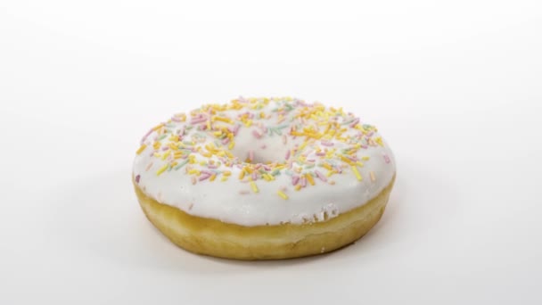 Вращающийся пончик с белой глазурью на белом фоне — стоковое видео