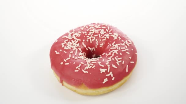 Крутящийся пончик с розовой глазурью на белом фоне — стоковое видео