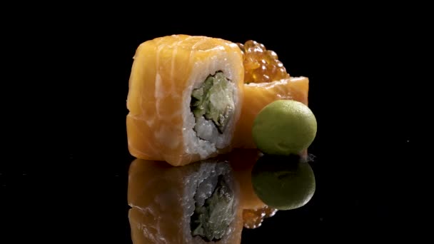 Sushi roll gedraaid op zwarte achtergrond. Sushi Japans eten in restaurant. Sushi van de California roll set met zalm, fruit, vliegende vis roe en kaviaar close-up. Het menu van het restaurant van Japan. 4k Uhd — Stockvideo