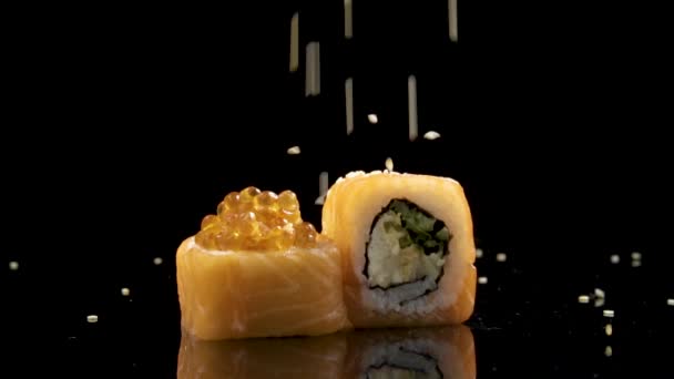 Slowmo sushi roll met zalm en kaviaar op zwarte achtergrond draaien. — Stockvideo