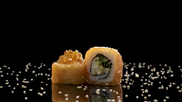 Sushi roll with salmon and caviar on black background rotating. — Stock Video