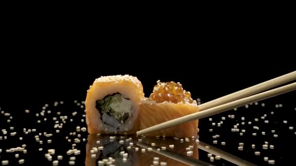 Sushi roll with salmon and caviar on black background rotating. — Stock Video