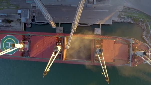 Vista de cerca del buque cargando cultivos de grano en un carguero a granel a través del tronco para abrir bodegas de carga en la terminal del silo en el puerto marítimo. Transbordo a granel de cereales a buque. Transporte de productos agrícolas . — Vídeo de stock