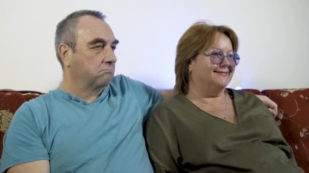 Porträtt av ett lyckligt moget par i deras hem tittar på tv tillsammans — Stockvideo