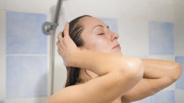 La mujer que se relaja bajo el agua corriente en la ducha caliente . — Vídeo de stock