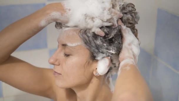 La Jeune femme prenant une douche et se lavant les cheveux avec le shampooing . — Video