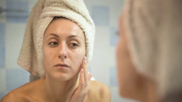 Chica unta la cara con una crema después del baño. Cuidado de la piel — Vídeos de Stock