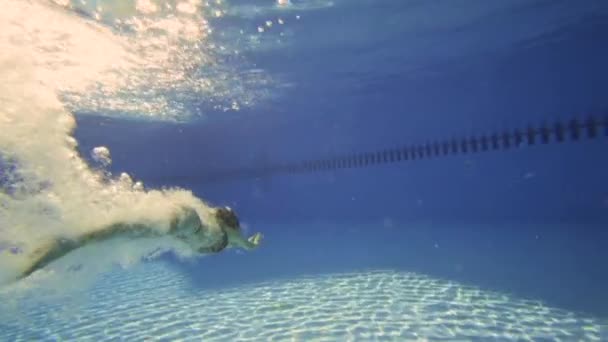 Kvinnan i Bikini simma under vattnet med vacker sol nödraketer i slow motion. — Stockvideo