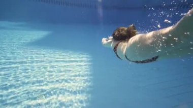 Genç kız yüzme havuzunda su altında yüzüyor. Ağır çekim.