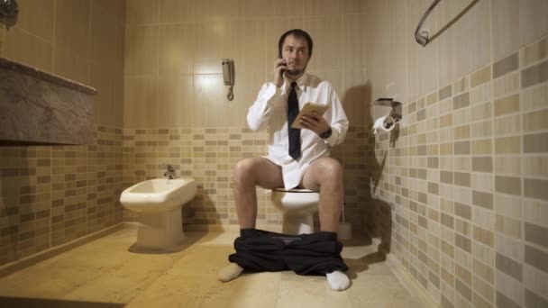 Muž sedí na záchodě v luxusní toaletu s telefonem a práci. 4k — Stock video