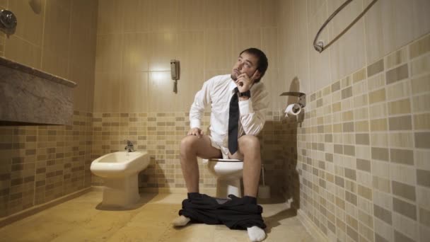 The man sitting on the toilet in a restroom and thinking. 4k — Stock Video