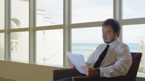 El hombre de negocios en el vestíbulo trabajando con documentos — Vídeos de Stock