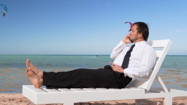 Un jeune homme d'affaires travaille sur la plage. Homme professionnel est assis dans une chaise longue confortable — Video