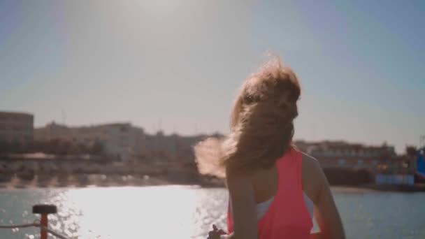 Een jong meisje loopt bij zonsondergang langs de zee — Stockvideo