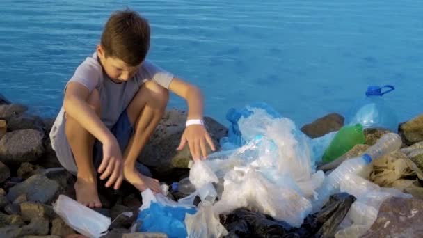 Niño voluntario limpiando la playa en el océano. Concepto de ecología segura . — Vídeos de Stock