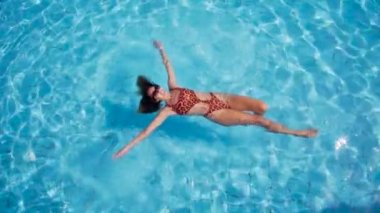 Yukarıdan, berrak sularda yüzen güzel genç kadın göster