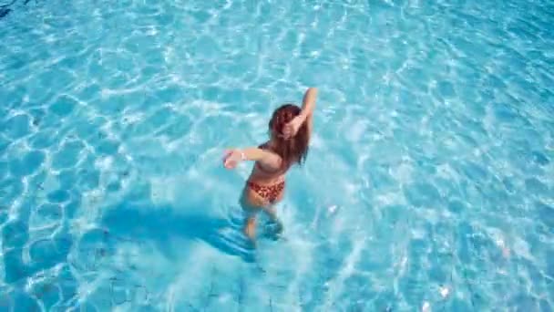 A lány táncol a medencében, terjed a kezét, a víz, és teszi a fröccsenő — Stock videók