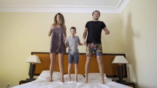 Família feliz com o filhinho pulando na cama em casa — Vídeo de Stock