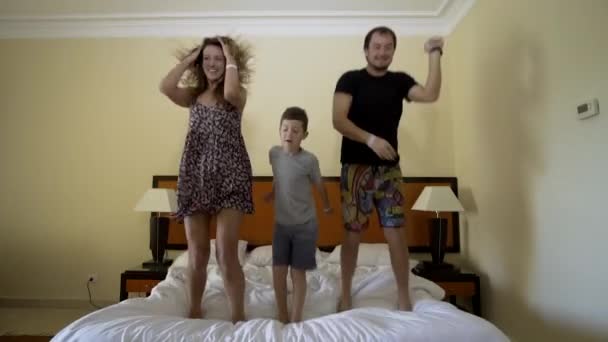 Boldog család és ugrás az ágyon. Boldog családi koncepció. Apa, anya és kis fiú ugrik az ágyon — Stock videók