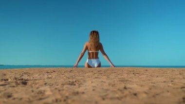 Deniz arka plan üzerinde oturan bir beyaz mayo güzel kız