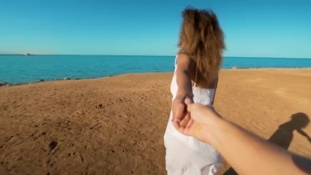 Folgen Sie mir einer jungen Frau, die ihren Freund an die Küste zieht. das Mädchen hält die männliche Hand und rennt zum Strand, zum Meer. Sommerurlaub oder Urlaub. — Stockvideo