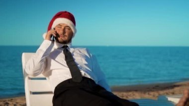 santa claus şapka bir tembel deniz arka plan üzerinde oturan işadamı