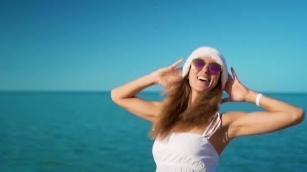 La muchacha feliz en el sombrero de santa claus se alegra en el mar — Vídeos de Stock
