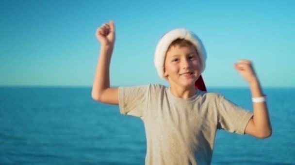O menino em Papai Noel se alegra no mar — Vídeo de Stock