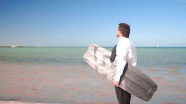İşadamı sahil üzerinde duruyor ve Yönetim Kurulu kitesurfing tutar