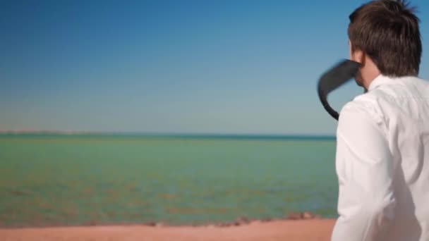 De zakenman in pak loopt naar de zee met een bord kitesurf — Stockvideo