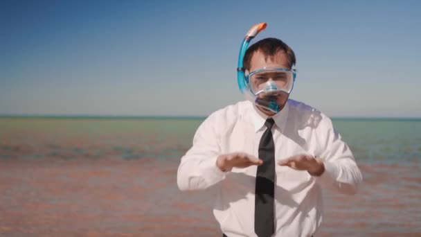 Han affärsman på bakgrunden av ett vackert hav i en mask och snorkel imiterar simning — Stockvideo