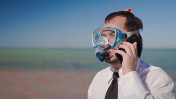 O homem de negócios na praia falando ao telefone com uma máscara de snorkel e snorkel — Vídeo de Stock