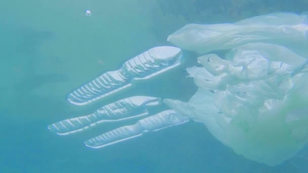 Pollution plastique dans l'océan problème environnemental. Tasses, sacs de transport, bouteilles et pailles en plastique immergés dans la mer 