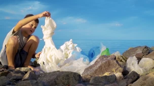 Litle παιδί εθελοντικό καθαρισμό στην παραλία στη θάλασσα. Έννοια ασφαλής οικολογία. — Αρχείο Βίντεο