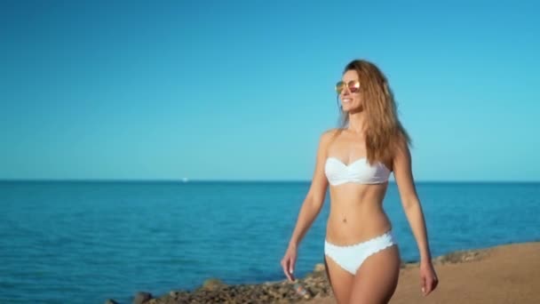 Sexig kvinna i vit bikini promenader på stranden på solig dag. — Stockvideo