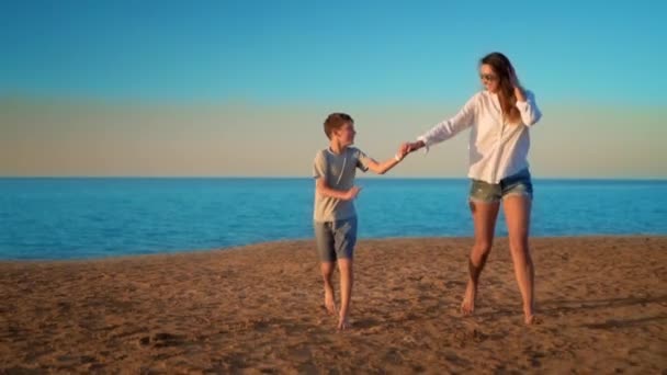 La madre y el hijo corren por el mar de la mano — Vídeos de Stock