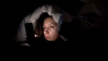 Genç kadın ile smartphone yatakta. Cep telefonu cihaz 4 k yatağa gitmeden önce oynadığı kadın