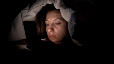 Genç kadın ile smartphone yatakta. Cep telefonu cihaz 4 k yatağa gitmeden önce oynadığı kadın