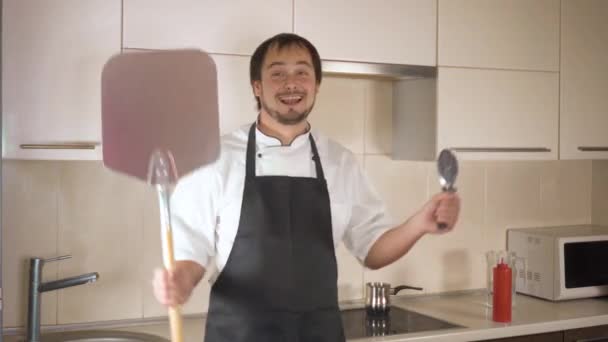 Attractive young funny man dancing while cooking in the kitchen at home — Stock Video
