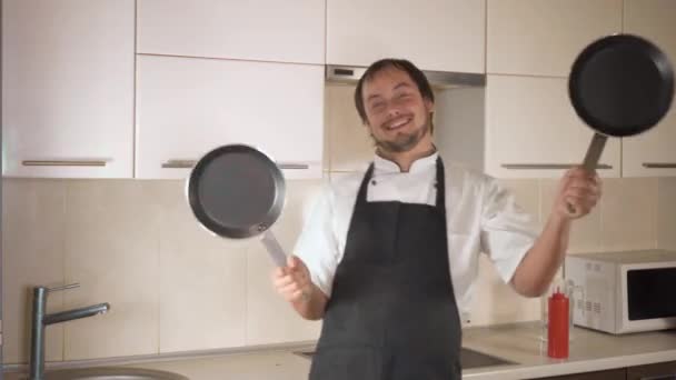 Привлекательный молодой смешной человек танцует во время приготовления пищи на кухне дома — стоковое видео
