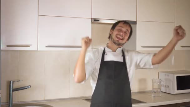 有吸引力的年轻有趣的男人跳舞, 而在厨房在家里做饭 — 图库视频影像