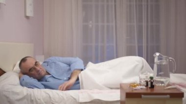 Hastane yatakta yatarken üzgün komuta sizde. Yaşlı hasta hastanede yalnız ve düşünme hissediyor. Tıbbi bir klinik yatan yatan hasta yaşlı adam.